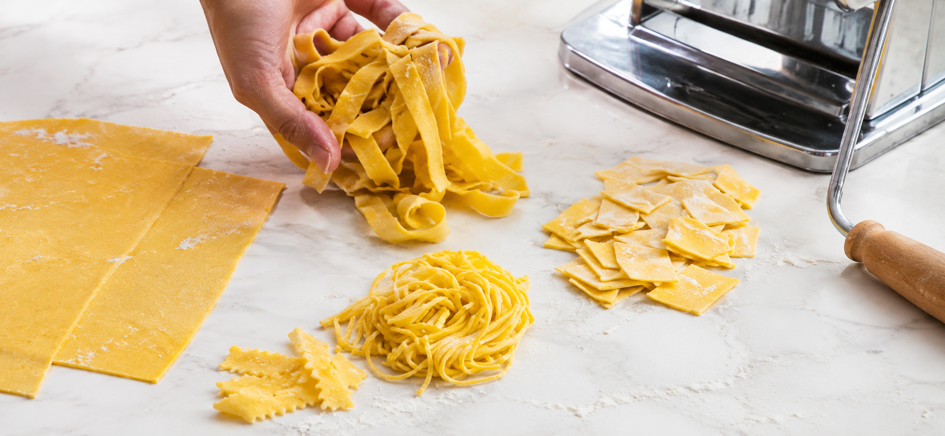 Mains préparant des tagliatelles de pâte, amas de nouilles coupées et pâtes sèches sur plan de travail.